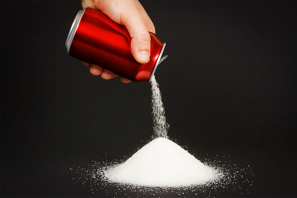 Sugary soda being poured into a glass, symbolizing its negative health effects